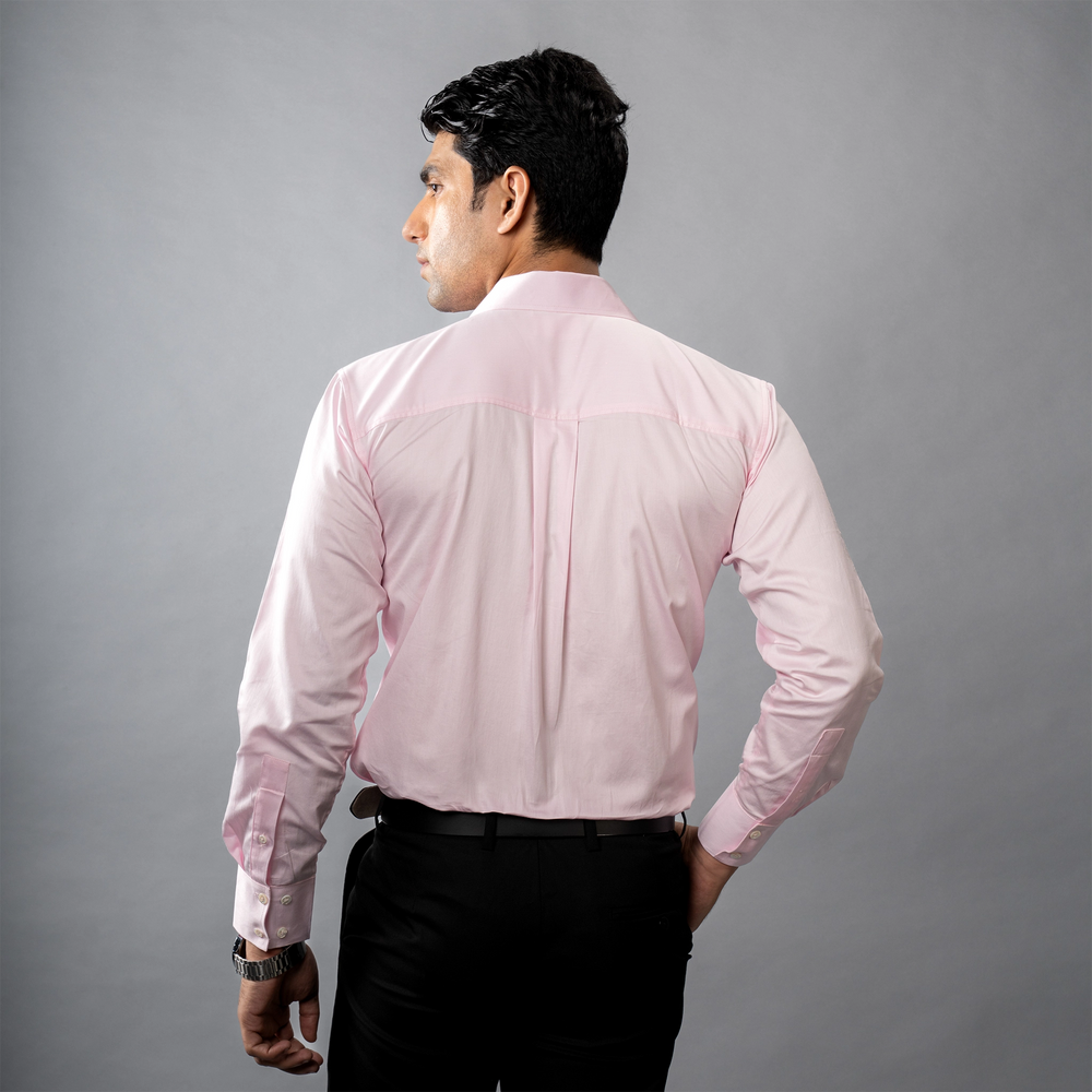 Man wearing a formal light pink shirt against a gray background