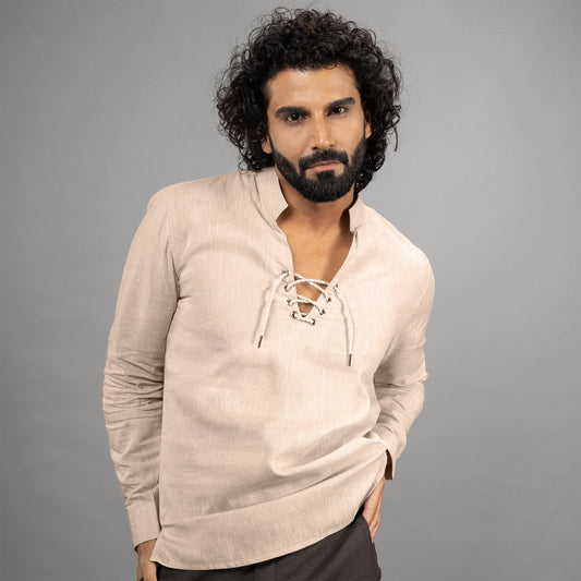 Man wearing a beige long-sleeve shirt with lace-up details against a grey background