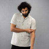 Man looking down wearing a Oil Green colored shirt against a grey background