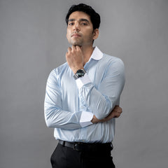 Man posing wearing a brand appril light blue shirt with against a gray background