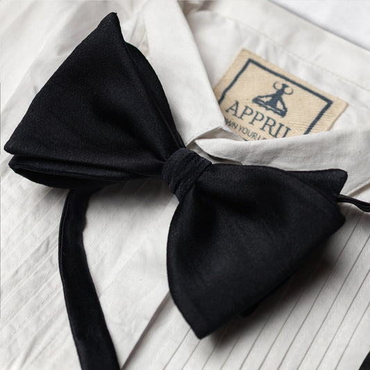 Black bow tie on a white shirt with a visible appril brand label.