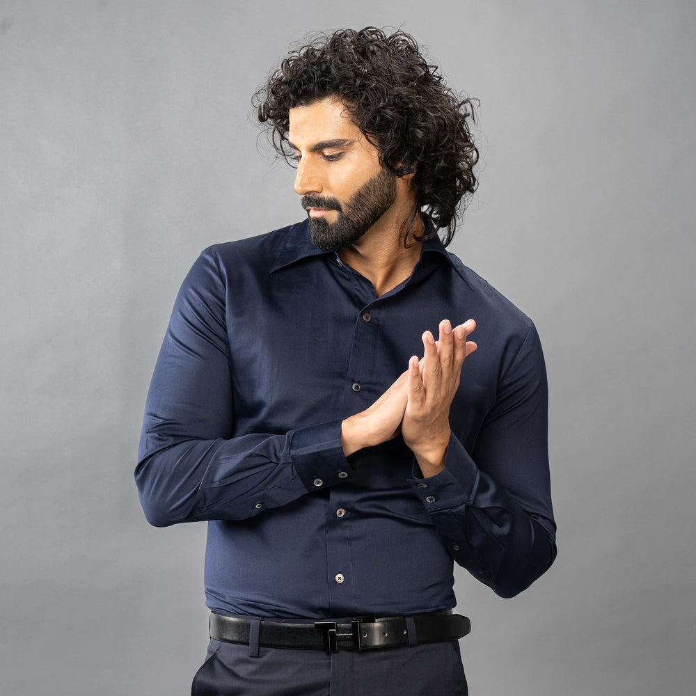 Man in a Maritime Blue shirt with hands clasped in front of a grey background