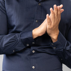 Person wearing a Maritime Blue natural mother‑of‑pearl buttons -up shirt with hands clasped in front