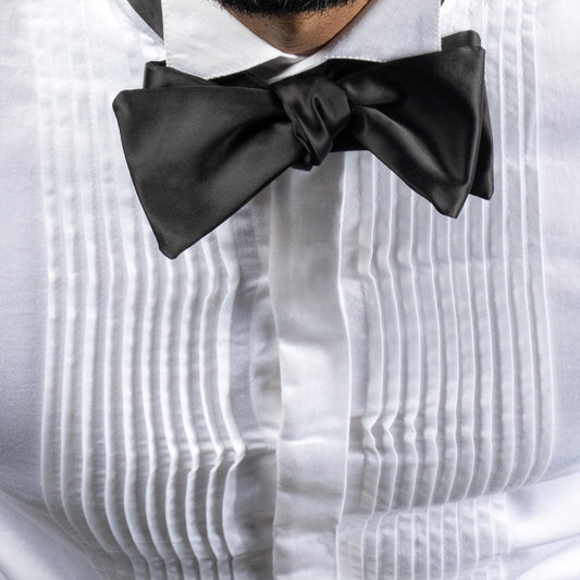 Black bow tie on a white shirt with pleated details