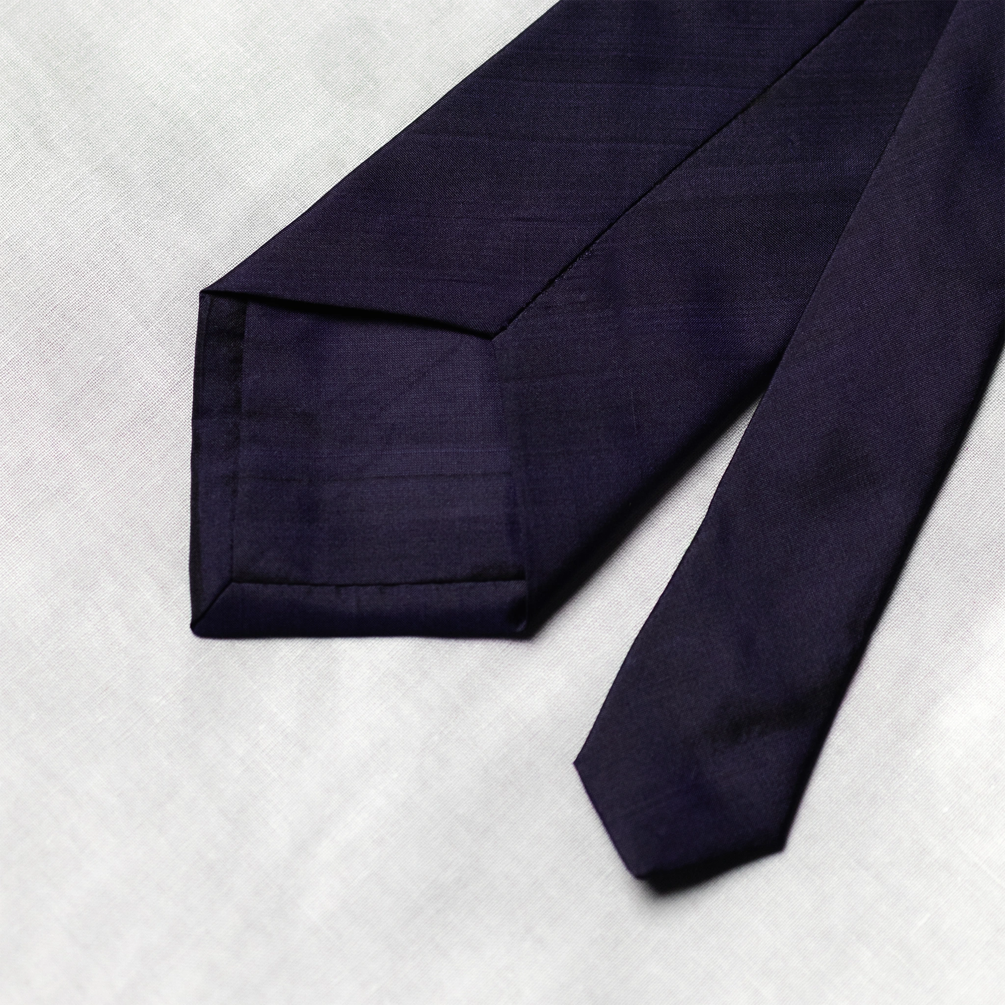 back of Navy blue tie on a light gray background