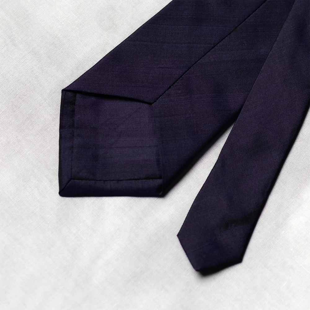 back of Navy blue tie on a light gray background