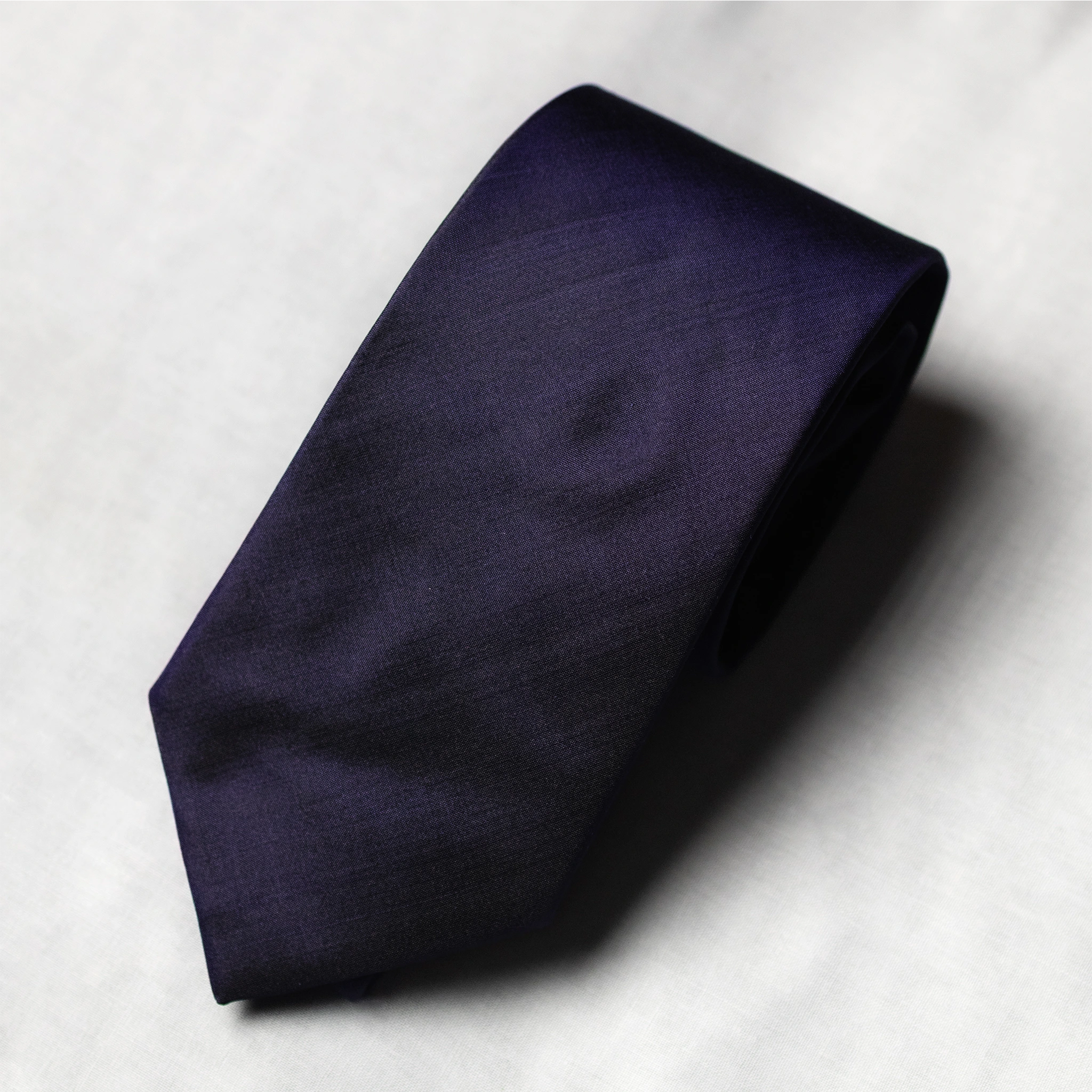 Navy blue tie on a light gray background