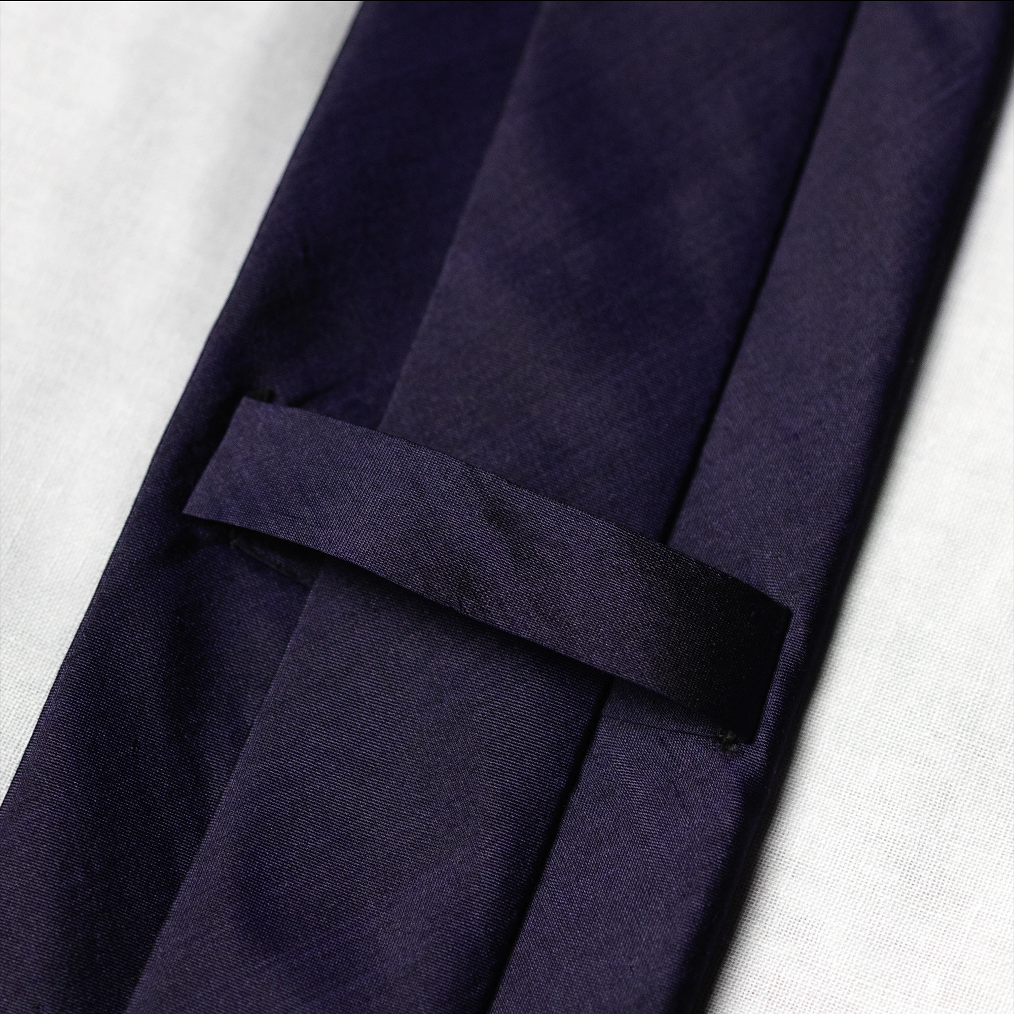 Navy blue tie keeper loop on a white background