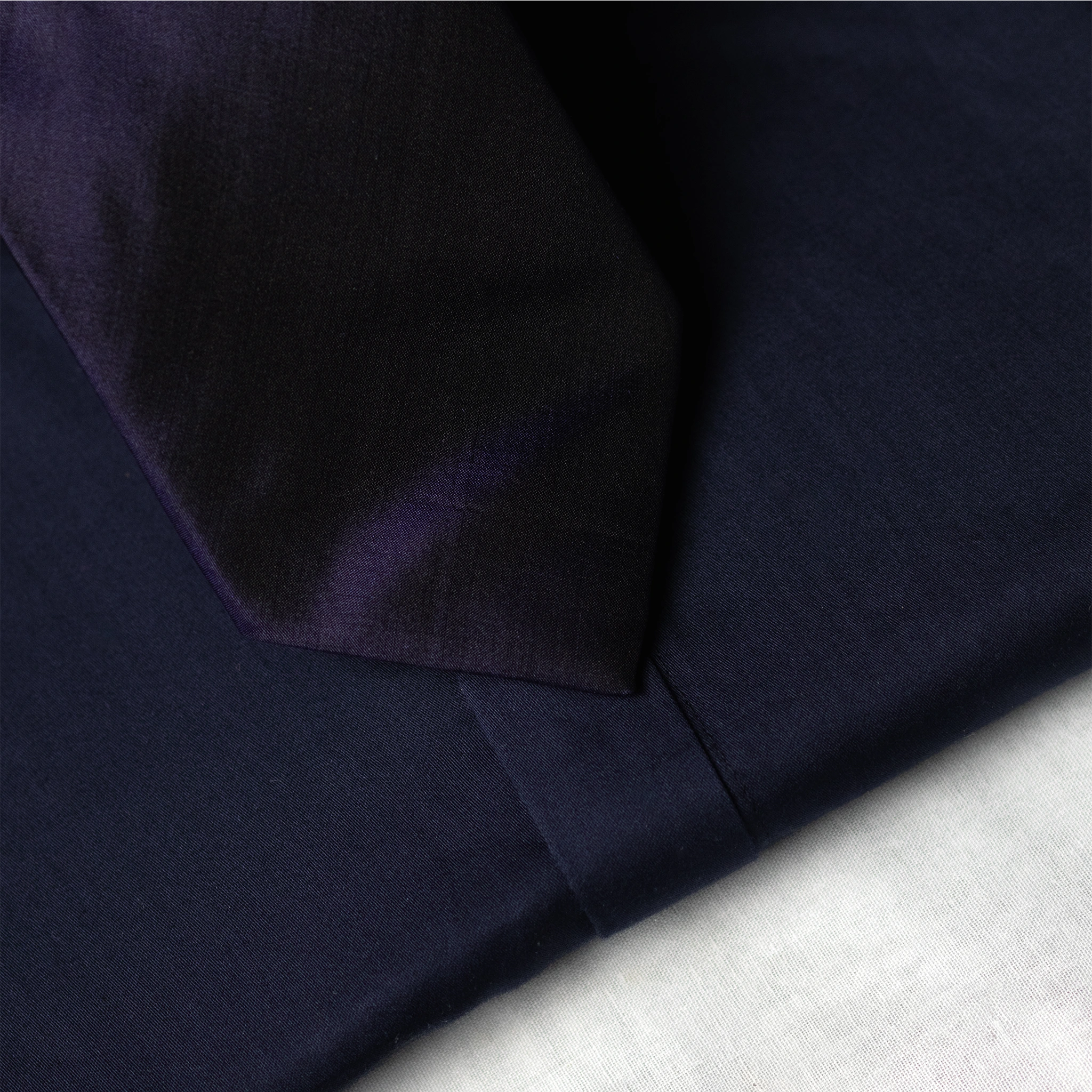 silk fabric Navy blue tip of tie with a subtle texture on a light grey background
