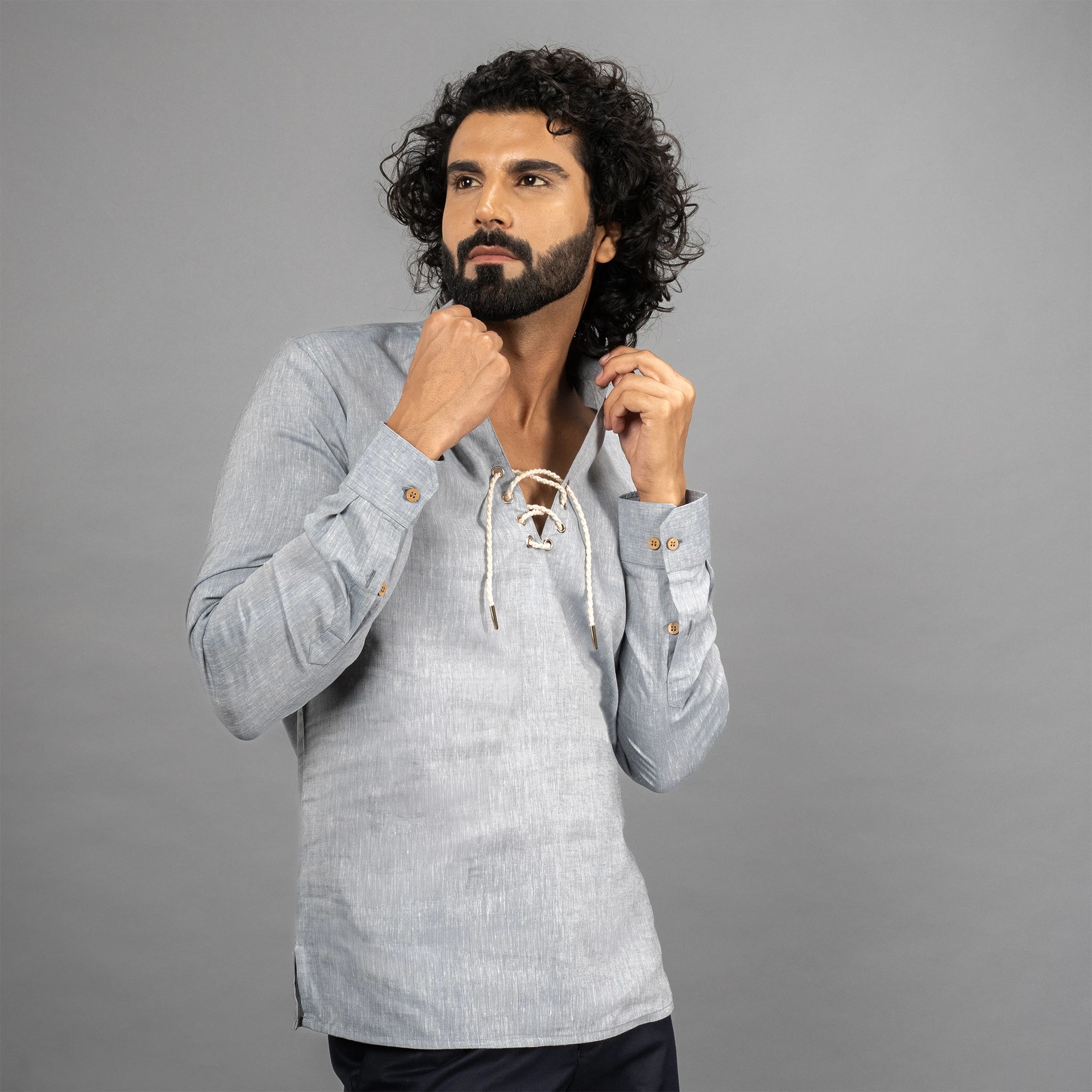 Man wearing a Faded Denim long-sleeve shirt with a lace-up front against a grey background.