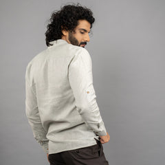 A maritime‑inspired lace‑up linen shirt with roll‑up sleeves, metal eyelets, and coconut shell button closures. posing backward