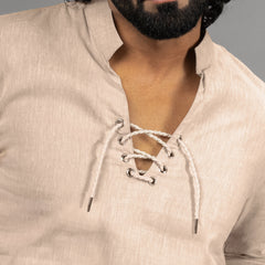 Close-up of a beige shirt with lace-up details worn by a person.