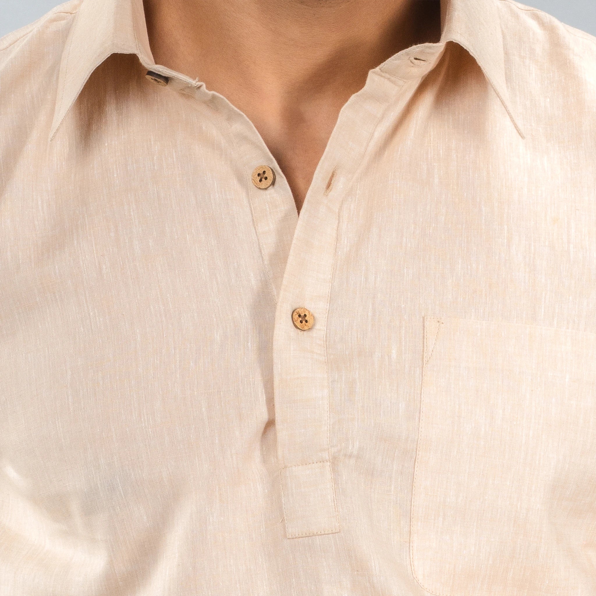 Close-up of a beige button-up lenin shirt with a neutral background