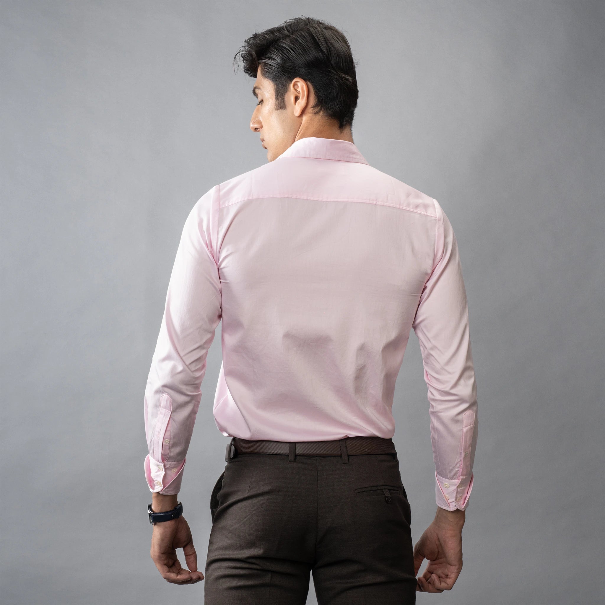 Man wearing a formal Petal Pink shirt against a gray background posing backward
