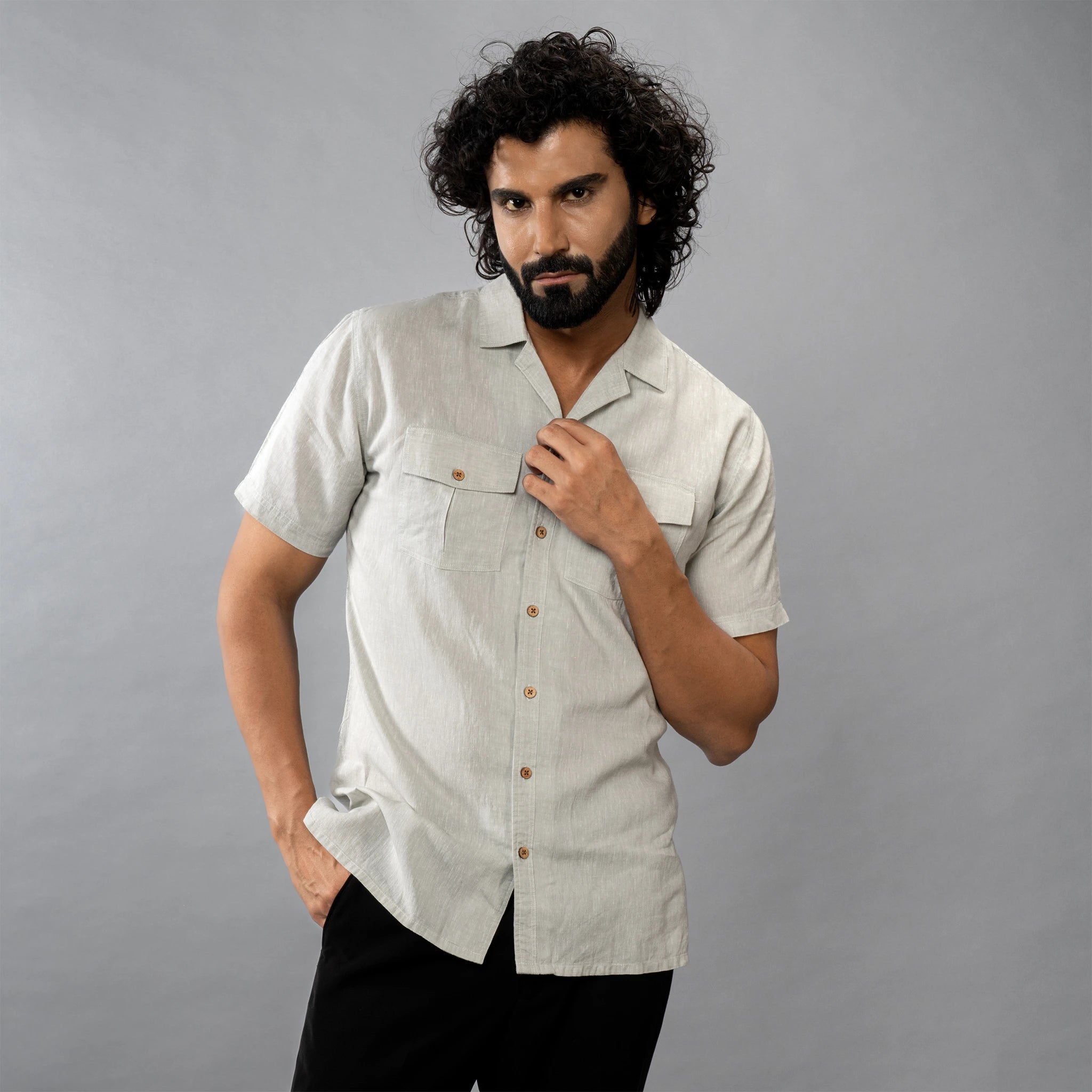 Man posing wearing a oil green shirt with short sleeves against a grey background