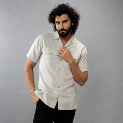 Man posing wearing a oil green shirt with short sleeves against a grey background