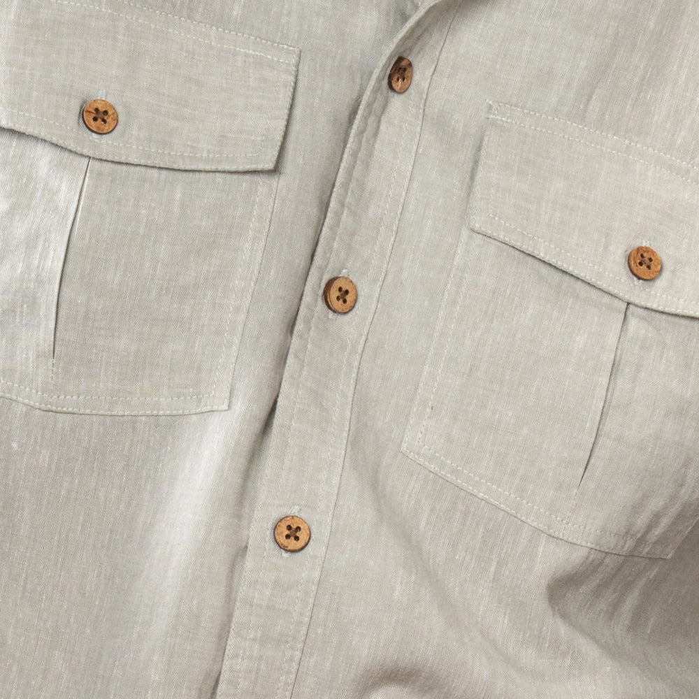 Close-up of a light oil green shirt with button details on a neutral background