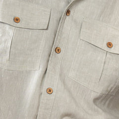Close-up of a light oil green shirt with button details on a neutral background