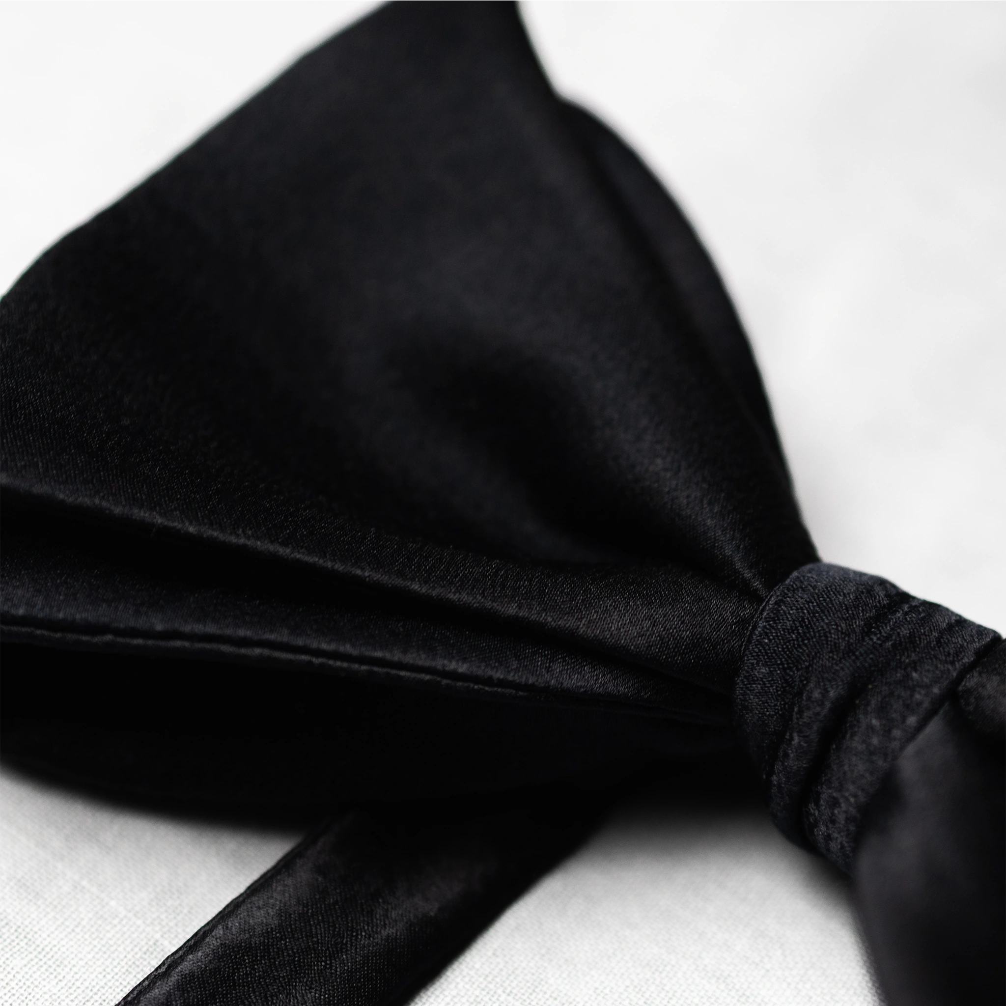 Black satin fabric bow tie on a white background