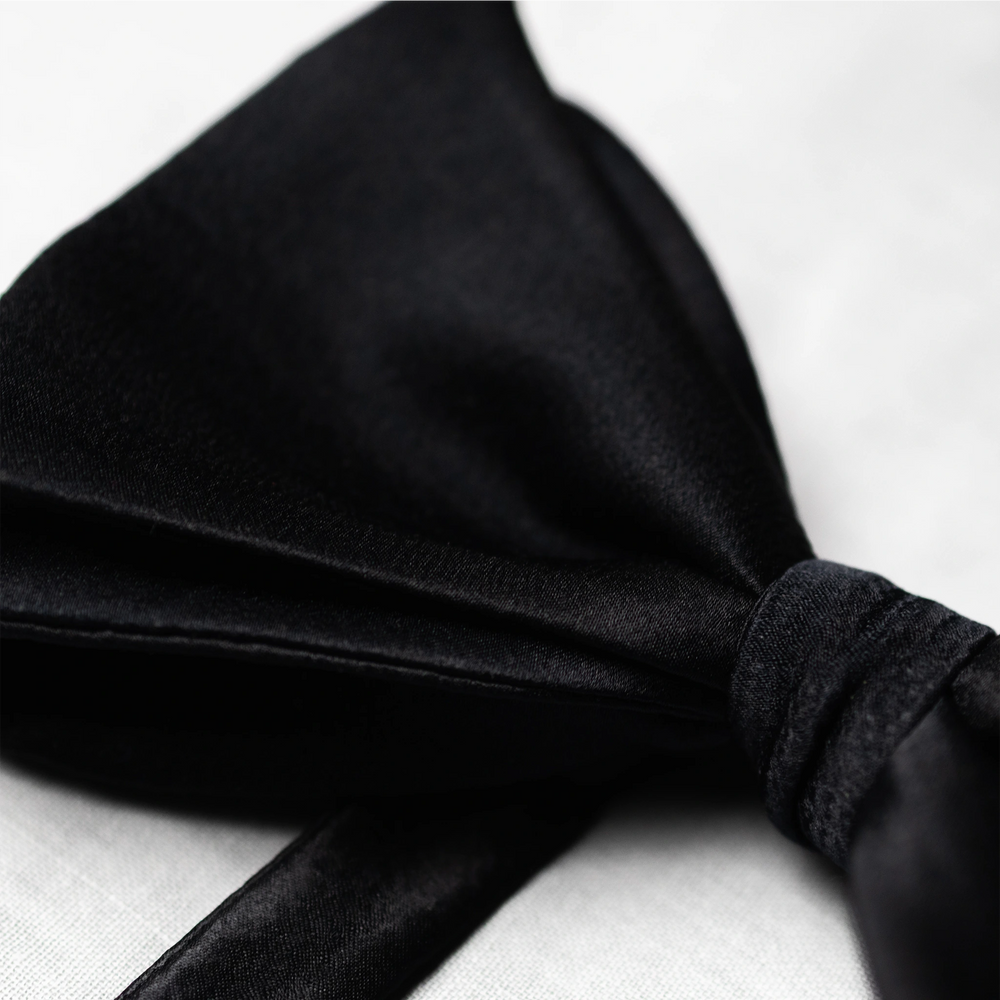 Black satin fabric bow tie on a white background