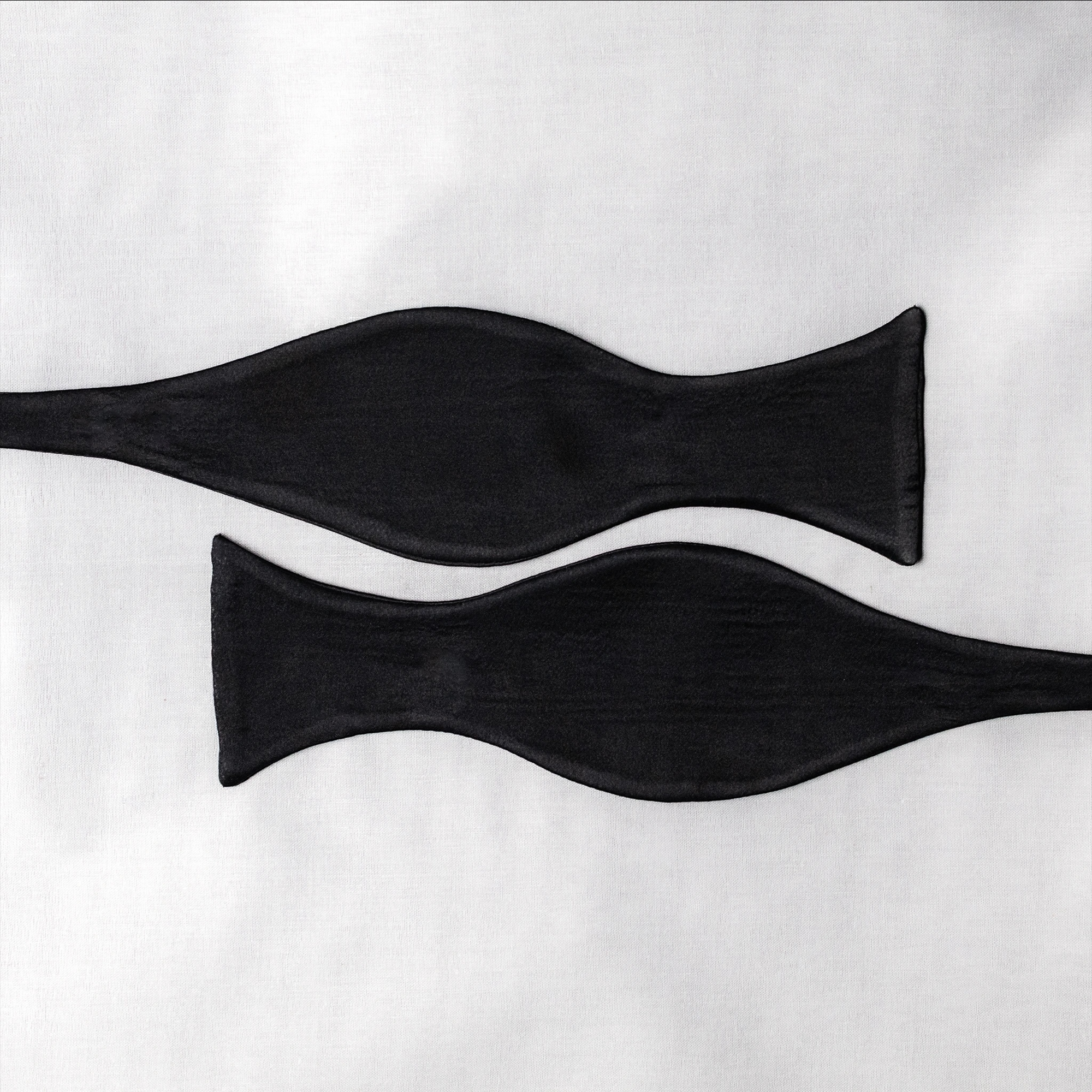 Two black satin  bow tie open pieces on a white background
